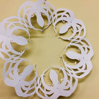 Circular paper cutout featuring a repeating pattern of white octopuses on a beige background.