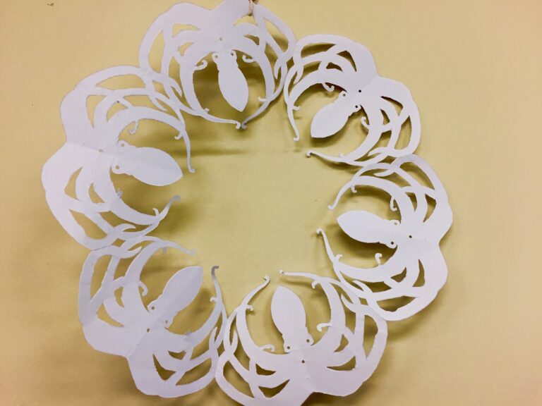 Circular paper cutout featuring a repeating pattern of white octopuses on a beige background.