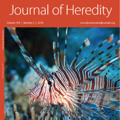 A lionfish swims near coral, featured on the cover of the Journal of Heredity, Volume 109, Number 2, 2018.