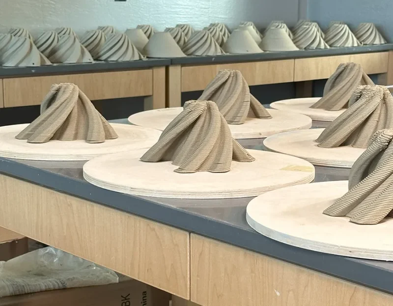 Spiral clay sculptures on round boards displayed on a wooden table in a workshop setting.